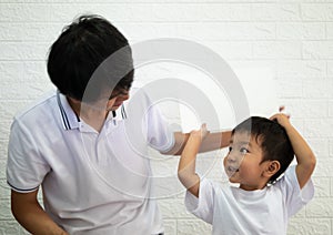 Asian child boy holding white board on head with dad with happy smiling face.