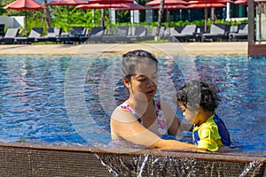 Asian child boy learn swimming in a swimming pool with mom