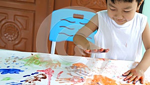 Asian child boy painting hands on paper at home. Kid playing watercolor with happy moment.