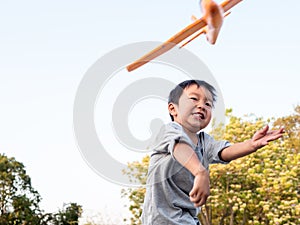 Asian child boy play plane toy to sky outdoor in nature background.