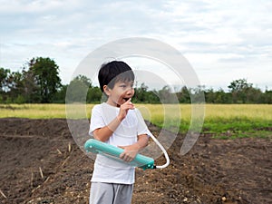Asian child boy playing, blowing melodeon musical instrument. Kid make music song with happy relaxing face in nature field