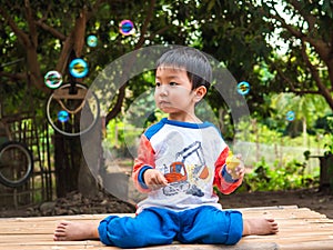 Asian child boy playing bubbles outdoor with happy smiling face with natural rural green background.