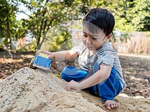 Asian child boy playing car toy on sand outdoor with cute face in nature background.