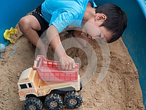 Asian child boy playing car toy in sandbox outdoor