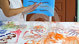 Asian child boy playing hands  painting on paper at home. Kid playing watercolor with happy moment.