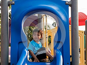 Asian child boy playing in playground. Young kid having happy moment in summer.