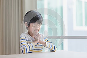 Asian child boy praying with eyes closed in the morning