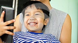 Asian child boy smiling with happy face, hand holding smartphone