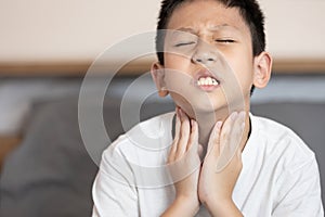 Asian child boy touching his neck,loss of the voice,hoarseness,voice is hoarse from Laryngitis or sore throat,difficulty photo