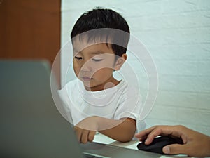 Asian child boy using notebook or computer for learning.