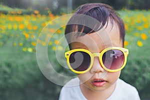 Asian child boy wearing yellow sunglasses outdoor