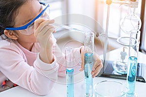 Asian child chemist holding flask and test tube in hands in lab learning chemistry experiment. Scientist chemistry and science