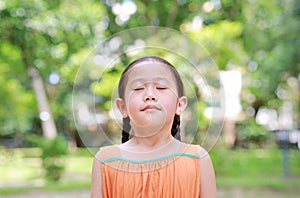 Asian child close their eyes in garden with Breathe fresh air from nature. Close up kid girl relax in green park for good health
