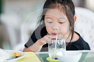 Asian Child Drinking Water Using Straw from Glass