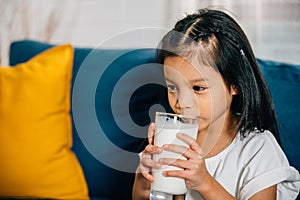 Asian child enjoys a glass of milk on the sofa their happiness and innocence