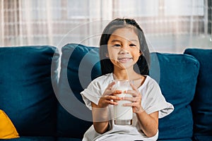 Asian child enjoys a glass of milk on the sofa their happiness and innocence