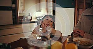 Asian child, family home and bored at dinner with parents for food, tired or night in dining room. Japanese kid