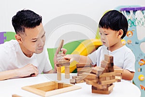 Asian child and father playing with wooden blocks in the room at home. A kind of educational toys for preschool and kindergarten