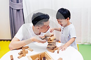 Asian child and father playing with wooden blocks in the room at home. A kind of educational toys for preschool and kindergarten