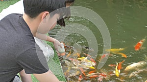 Asian child feeding fishes in a garden pond.