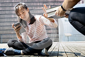 Asian child girl is avoiding reading book, say no,she wants to use a mobile phone to play games or chat with friends, teenage photo