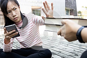 Asian child girl is avoiding reading book,she wants to use a mobile phone,addicted to smartphone,teenage student is refusing to photo