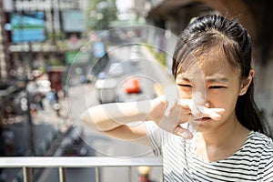 Asian child girl catches her nose because toxic fumes from car,bad smell,air pollution,dust allergies or sinus infection,female photo