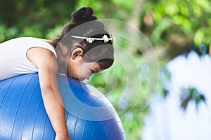 Asian child girl doing stretching exercise on fitness ball