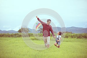 Asian child girl and father with a kite running and happy on meadow in summer in nature