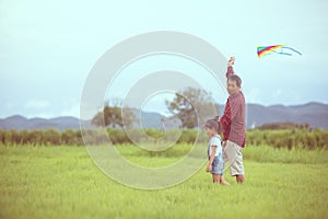 Asian child girl and father with a kite running and happy on meadow in summer in nature