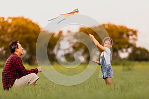 Asian child girl and father with a kite running and happy on meadow in summer in nature