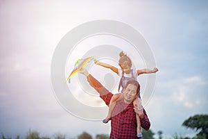 Asian child girl and father with a kite running and happy on meadow in summer in nature