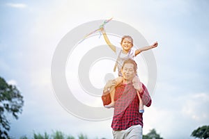 Asian child girl and father with a kite running and happy on meadow in summer in nature