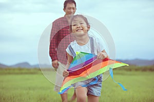 Asian child girl and father with a kite running and happy on meadow in summer in nature