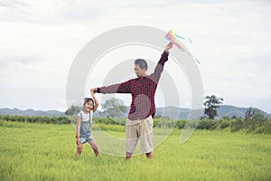 Asian child girl and father with a kite running and happy on meadow in summer in nature