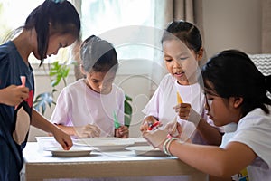 Asian child girl and friends are decorating cookies for party together with fun.