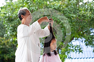Asian child girl getting haircut by grandmother at home