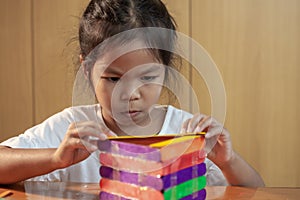 Asian child girl glueing colored ice cream sticks by hot melt electrical glue gun.