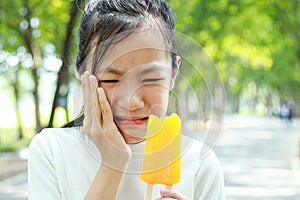 Asian child girl have hypersensitive teeth eating ice-cream,feel painful ,female teenage have sensitive teeth problem with ice- photo
