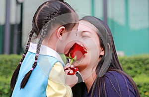 Asian child girl and her mother with kissing rose in the garden