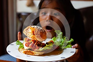 Asian child girl holding dish of delicious hamburger