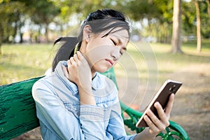 Asian child girl holding smartphone in hand, massage her neck,bending head reated to the pressure on the spine,stiff neck,muscles