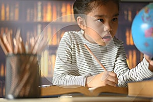 Asian child girl industrious is sitting at a desk indoors. Kid is learning in home