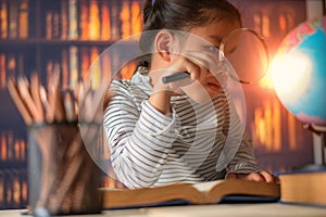 Asian child  girl  industrious  is sitting at a desk  indoors. Kid is learning in home