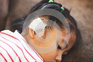 Asian child girl injured on the ear. Child`s ear with bandage after she has been accident