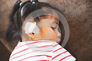 Asian child girl injured on the ear. Child`s ear with bandage after she has been accident