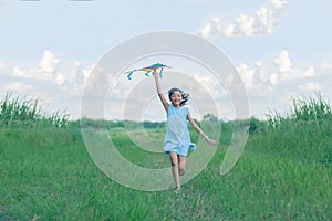 Asian child girl with a kite running and happy on meadow in summer in nature
