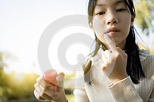 Asian child girl maintains her lips,skin care and protection, chapped lips,dry mouth that have lost moisture,beautiful female photo