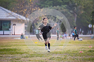Asian child girl making funny face and running with happiness in the soccer field. Child is happy after win in game.
