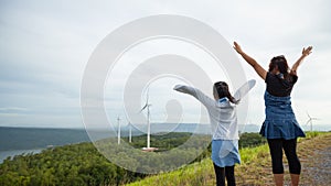 Asian child girl and mother raised their hands to fly and playing in the wind turbine field